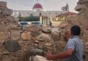 A man looks through a gap in a stone wall toward a Greek Orthodox church where gunmen opened fire during a funeral hours earlier in Hamoud village, in Jordan’s Karak governorate (AP)
