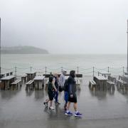 A family walks amongst empty picnic tables during bad weather (Gareth Fuller/PA)
