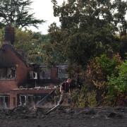A firefighter outside the burnt-out remains of a house following a huge blaze in Stourbridge, in the West Midlands (PA)