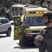 Israeli soldiers and emergency personnel gather near ambulances following a shooting attack carried out by Palestinian gunmen at a junction near Hebron (Mahmoud Illean/AP)
